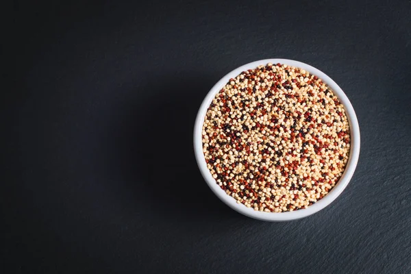 健康食品のコンセプト有機生キノア穀物ミックス ブラック スレート石のプレートに白いセラミック カップで 黒のコピー スペース — ストック写真