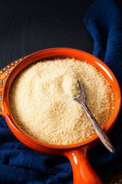 Gıda konsepti, portakal kâsesinde organik ham kuskus Blask taş tahtada fotokopi alanı ile.