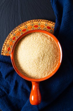 Gıda konsepti, portakal kâsesinde organik ham kuskus Blask taş tahtada fotokopi alanı ile.