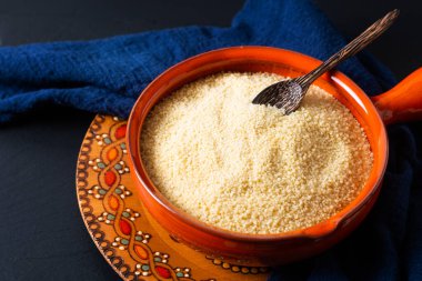 Gıda konsepti, portakal kâsesinde organik ham kuskus Blask taş tahtada fotokopi alanı ile.