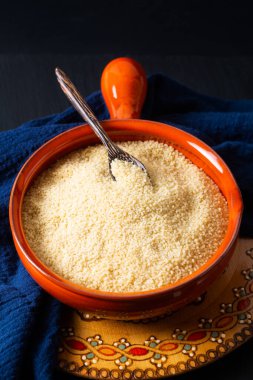 Gıda konsepti, portakal kâsesinde organik ham kuskus Blask taş tahtada fotokopi alanı ile.