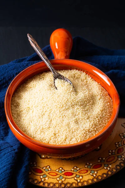 Gıda konsepti, portakal kâsesinde organik ham kuskus Blask taş tahtada fotokopi alanı ile.