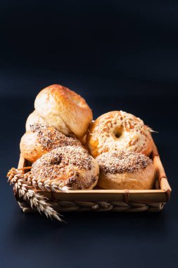 Yemek fırını konsepti. Siyah arka planda bambu hasır tepside ev yapımı organik simit.