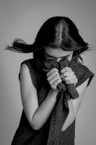 girl hides face in collar of dark sweater. Portrait in black and White