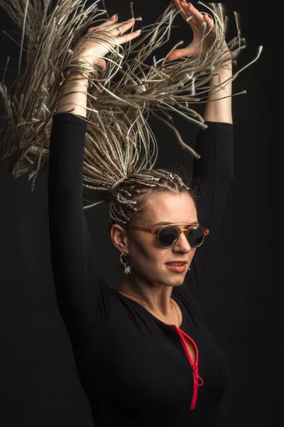 Fashion studio shoot woman with a creative colorful hairstyle in the form of a pigtail braided from dreadlocks Afro-pigtails in the technique of zizi.