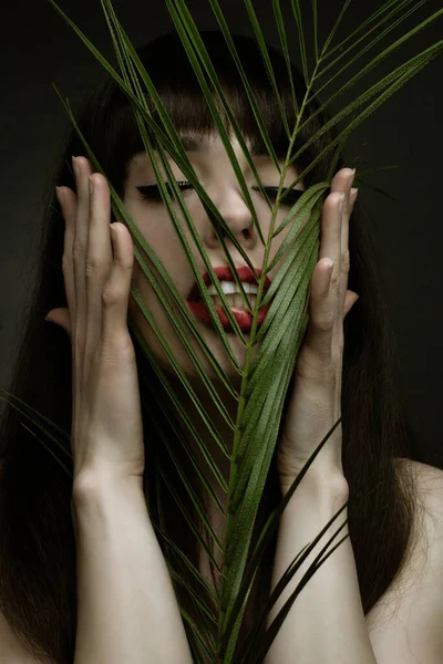 portrait of a young woman with leaf palms. Studio photo