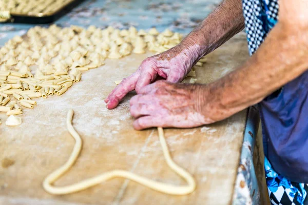 Yaşlı bir kadın, elleriyle hazırlarken Ökçe, tipik İtalyan makarnası..