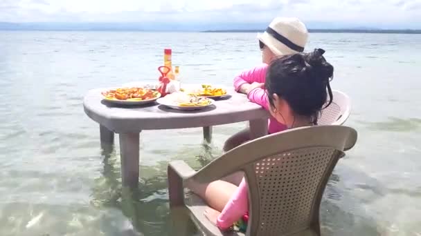 妈妈和女儿准备在海边的餐桌上吃饭 — 图库视频影像