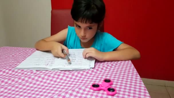 若い子は宿題をしながらスピンで遊ぶ — ストック動画