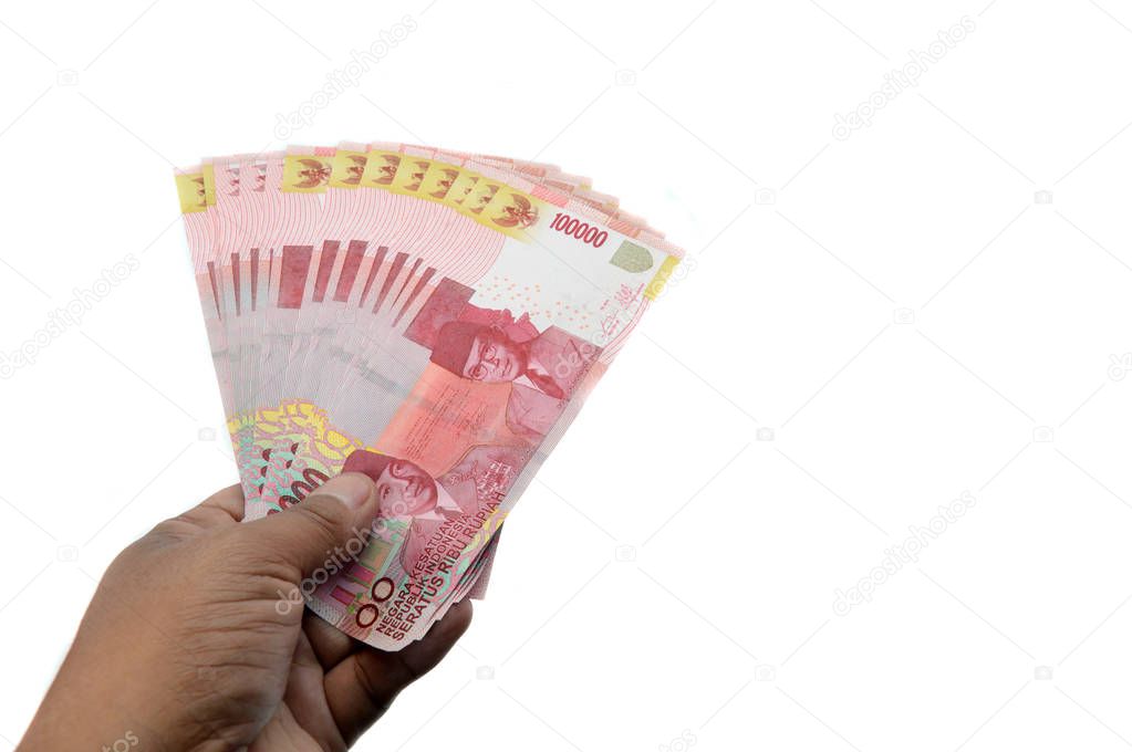 male hand hold one hundred thousand rupiah Indonesian paper money on white background