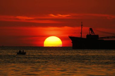 denizde gün batımında bir tanker silueti