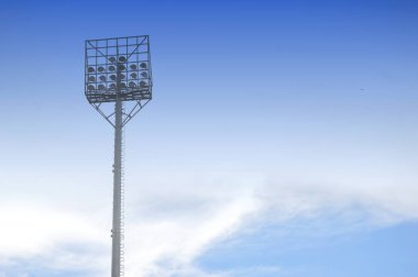 Beyaz bulutlu ve mavi gökyüzü arka planlı stadyum ışık direkleri