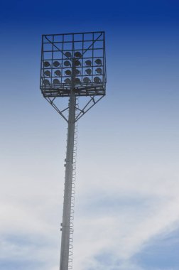 Beyaz bulutlu ve mavi gökyüzü arka planlı stadyum ışık direkleri