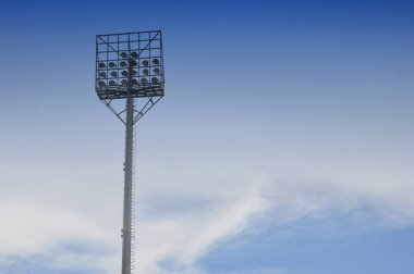 Beyaz bulutlu ve mavi gökyüzü arka planlı stadyum ışık direkleri