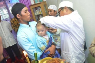 Tarakan, Endonezya. 12 Mart 2017 'de bazı alimler anne ve baba tarafından tutulan bebek için dua eder ve dua ederler.