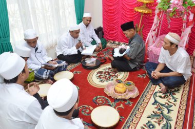 Tarakan, Endonezya. 26 Nisan 2016 'da bazı alimler bebeğin babası tarafından kucağına alınan bebek için dua eder ve ezbere okurlar.