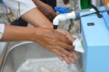 TARAKAN - INDONESIA, 27 March 2020 : Facilities for the general public to wash hands consisting of a water tank and sink to wash hands are provided by the Tarakan City government in the public area as an effort to prevent the spread of corona covid-1 clipart