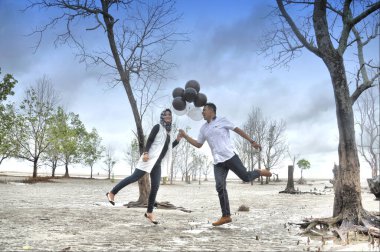 TARAKAN, INDONEZYA - 19 Şubat 2017: Endonezyalı gelin ve damat çiftlerinin sahilde günlük Müslüman elbiseleri giydikleri düğün öncesi fotoğraf çekimi