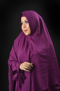 Siyah arka planda izole edilmiş menekşe başörtüsü takan güzel bir Müslüman kadının portresi.