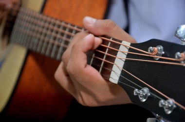 Adamın parmakları klasik ahşap gitar teli çalıyor.
