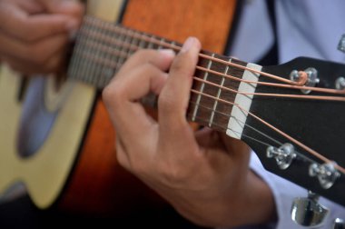 Adamın parmakları klasik ahşap gitar teli çalıyor.