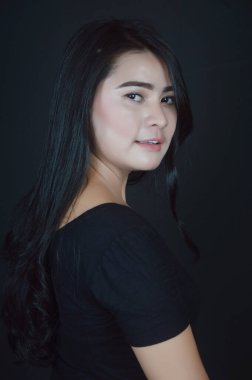 Siyah arka plan fotoğraf stüdyosunda siyah fotoğraf çeken Asyalı güzel bir kızın portresi.