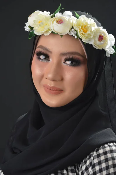ポートレート ビューティフル ムスリムのアジア系女の子 チェックされたモチーフのヒジャーブ 花のヘッドバンドを持つヒジャーブ 黒い背景のスタジオでの写真 — ストック写真