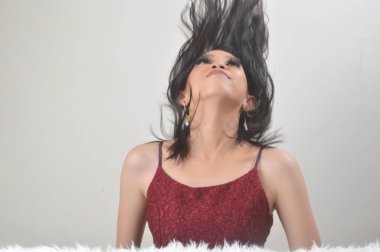 Güzel Asyalı Çinli kız, beyaz arka plan fotoğraf stüdyosunda kırmızı giyinmiş.