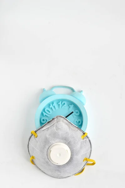 白い背景に隔離された目覚まし時計を覆う空気穴のある灰色のガーゼマスク — ストック写真