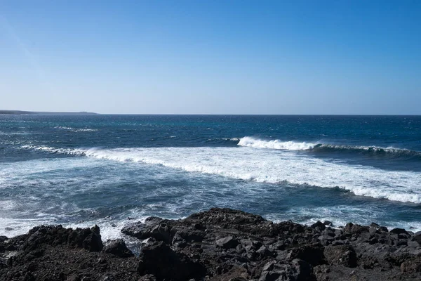 Ondas oceânicas na costa rochosa negra — Fotografia de Stock