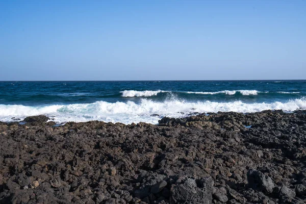 Zwarte vulkaan stenen op de rotsachtige kustlijn — Stockfoto