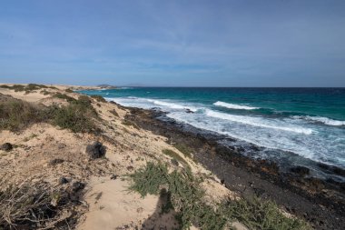 Deniz kıyısı üzerinde sarı kum ve siyah taşlar