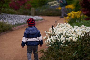 Küçük tanınmayan çocuk parkta çalışır ve güzel çiçekler kokuyor