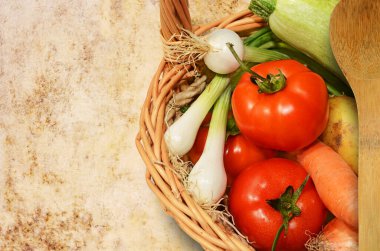 Eski masa örtüsünün üzerinde taze sebzeler.