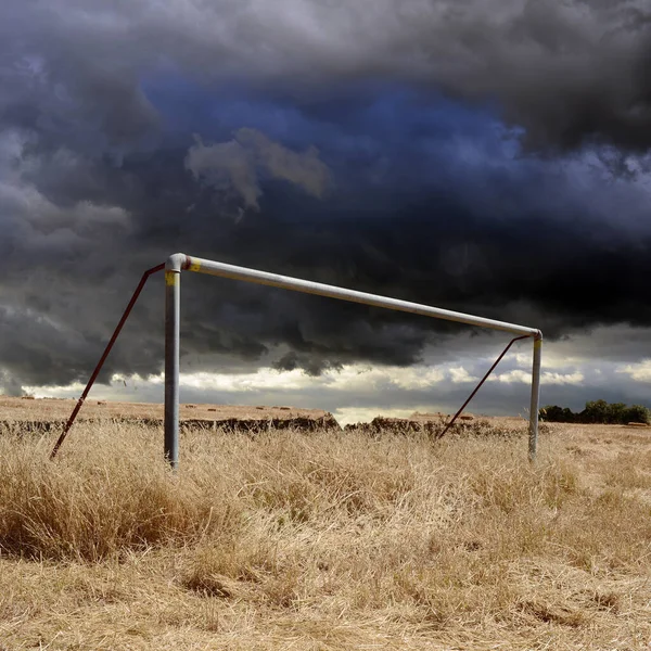 Fırtınalı gökyüzü olan ihmal edilmiş bir futbol sahası.