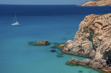 Yunanistan 'ın Milos Adası' ndaki Tsigrado plajının kayalıklarının yanında yat.