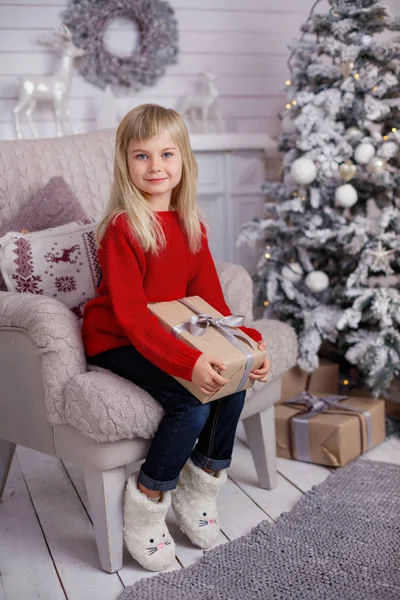 Cute little child girl with present. Kid holds a magic gift box near Christmas tree indoors. — Stock Photo, Image