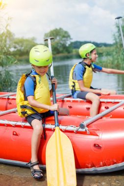 Sevimli çocuk kask ve kürek katamaran üzerinde rafting için hazır ile canlı yelek