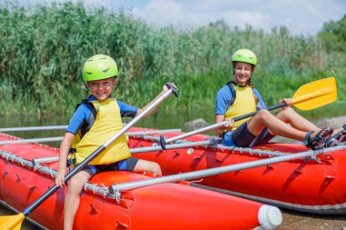 Sevimli çocuk kask ve kürek katamaran üzerinde rafting için hazır ile canlı yelek