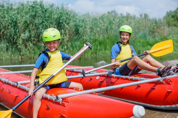 Cute boy in helmet and live vest with paddle ready for rafting on the catamaran — Stock Photo, Image