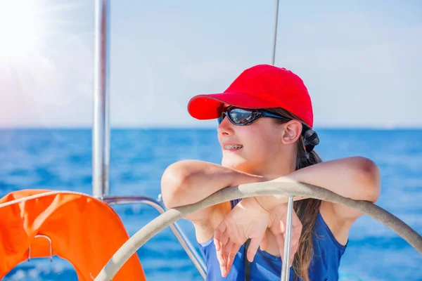 Chica capitán a bordo de yate de vela en crucero de verano. Aventura de viaje, yates con niños en vacaciones en familia . — Foto de Stock