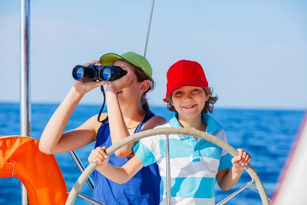 Chico capitán con su hermana a bordo de yate de vela en crucero de verano. Aventura de viaje, yates con niños en vacaciones en familia . — Foto de Stock