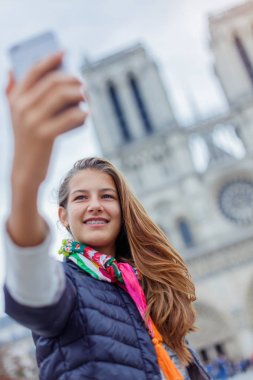 Genç turist kız selfie Notre Dame de Paris Katedrali ile alıyor. Fransa.