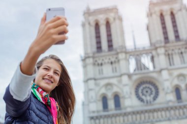 Genç turist kız selfie Notre Dame de Paris Katedrali ile alıyor. Fransa.