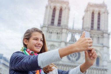 Genç turist kız selfie Notre Dame de Paris Katedrali ile alıyor. Fransa.