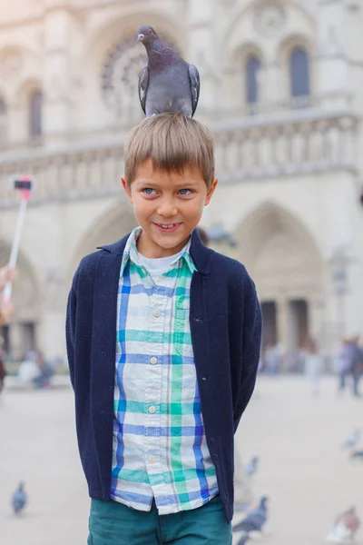 Niño con pájaros cerca de la catedral de Notre Dame de Paris en Paris, Francia — Foto de Stock