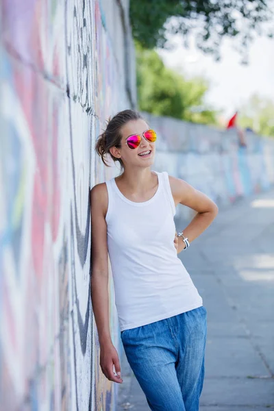 Flicka klädd Tom vit t-shirt, jeans poserar mot grov gatan vägg — Stockfoto