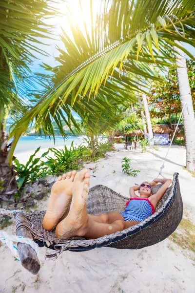 Glückliches Mädchen entspannt sich an einem tropischen Strand in der Hängematte. — Stockfoto