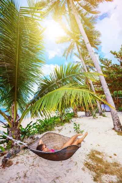 Glückliches Mädchen entspannt sich an einem tropischen Strand in der Hängematte. — Stockfoto