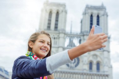 Genç turist kız selfie Notre Dame de Paris Katedrali ile alıyor. Fransa.